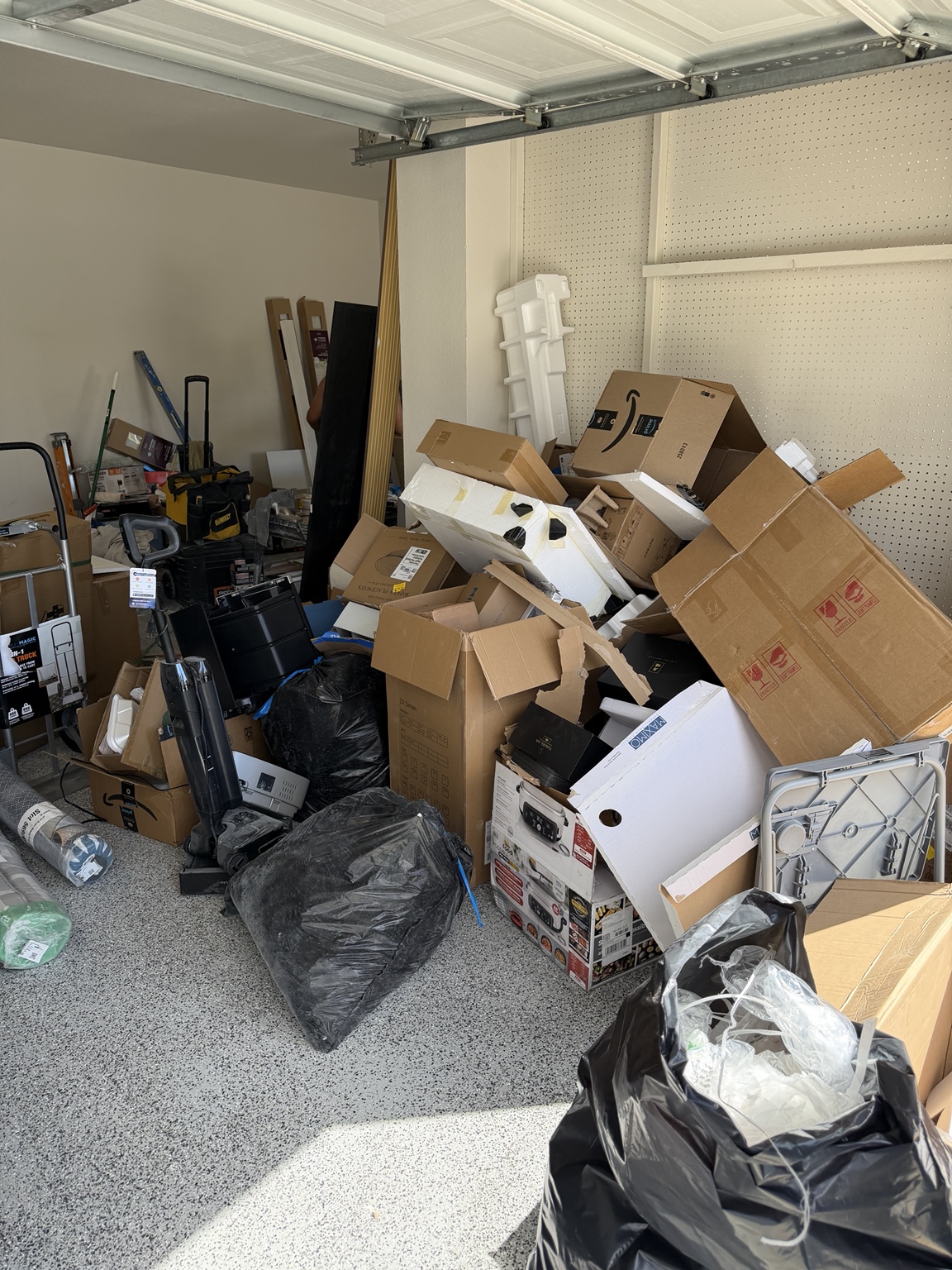 Before: cardboard boxes, packing foam and bags filling a garage corner